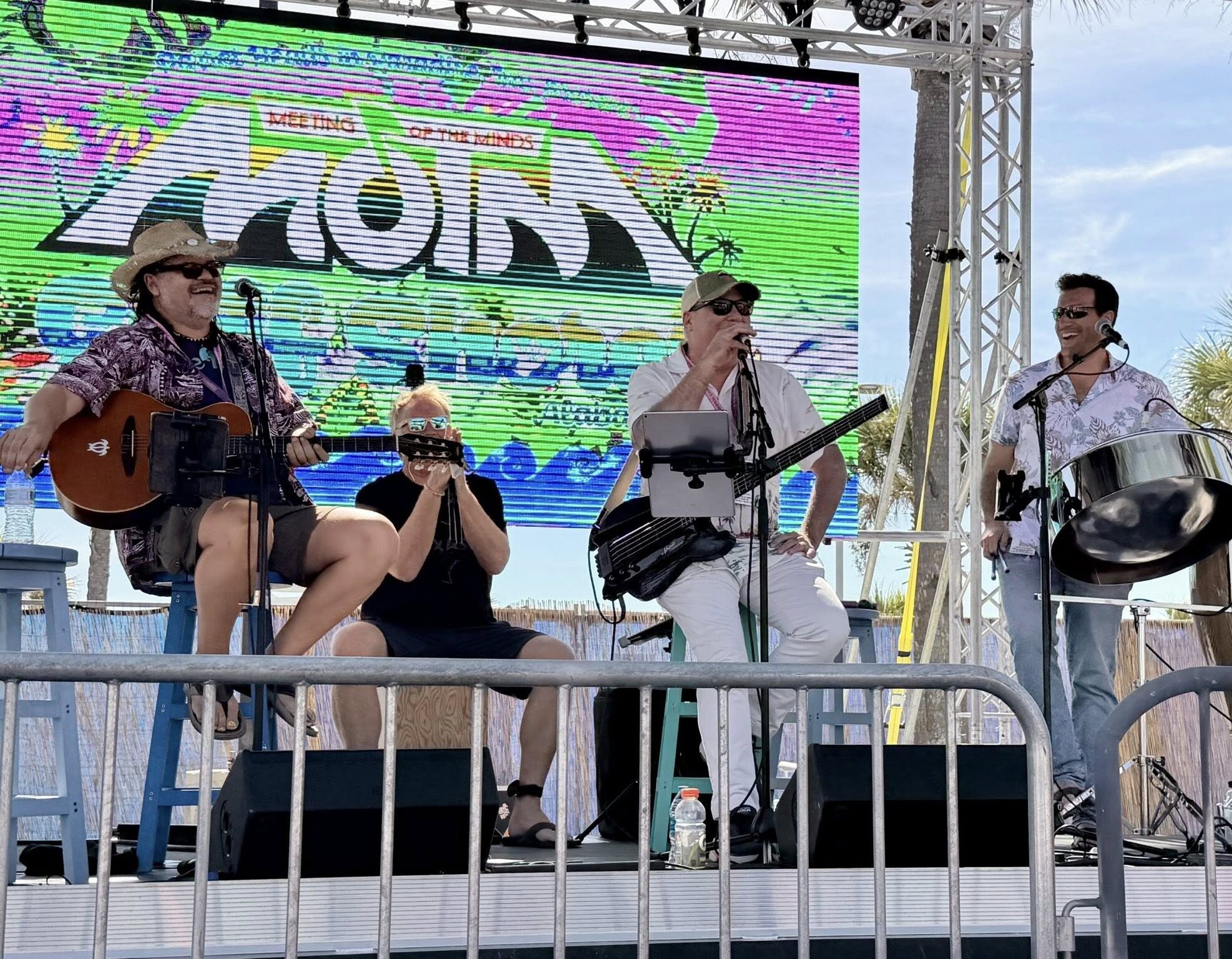 2 Live outdoor performance with guitarist, bassist, drummer, keyboardist, and steel pan player.