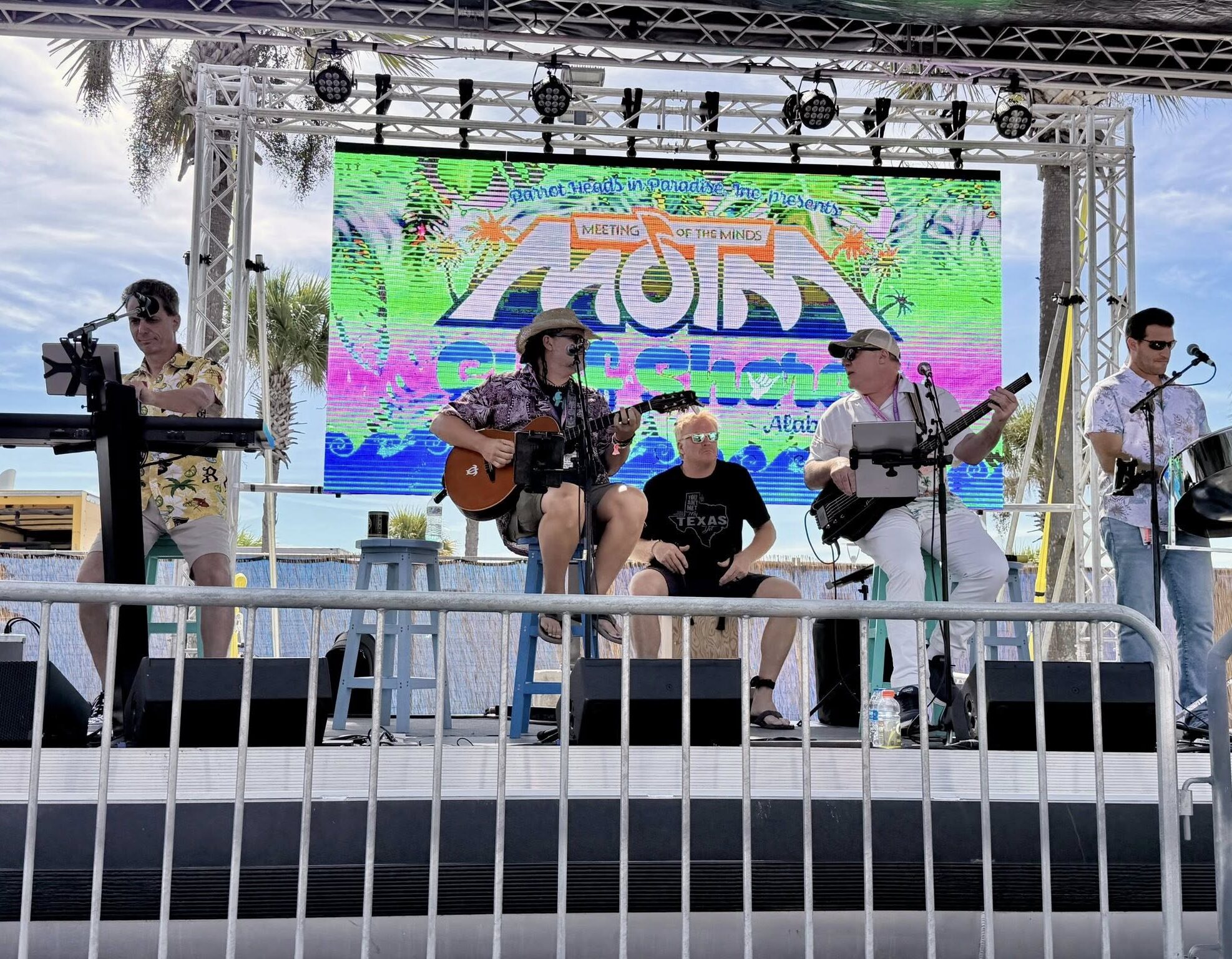 6 Outdoor performance with guitarist, bassist, drummer, keyboardist, and steel pan player.